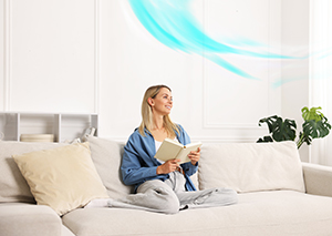 Woman reading on couch enjoying clean, circulated air after furnace repair in Ocean County