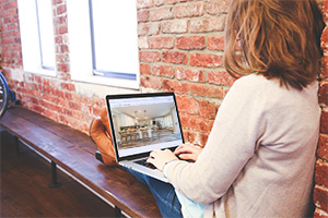 Woman sitting on a bench browsing homes for sale in Ocean County NJ on a laptop